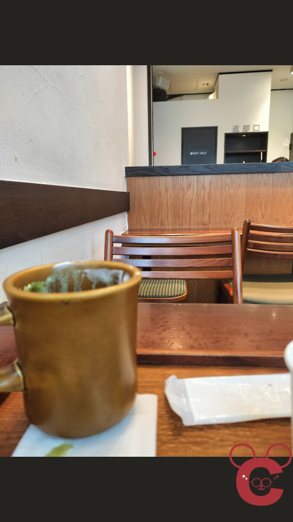 京都市中京区の「中岡慎太郎寓居跡」に建つカフェ「抹茶館」の店内風景。飲み終わった後の抹茶ラテのカップと、落ち着いた雰囲気の誰もいない客席（椅子やテーブル）を撮影した写真。歴史スポットでの休息を表現した中岡慎太郎ランドの記事用スライド。