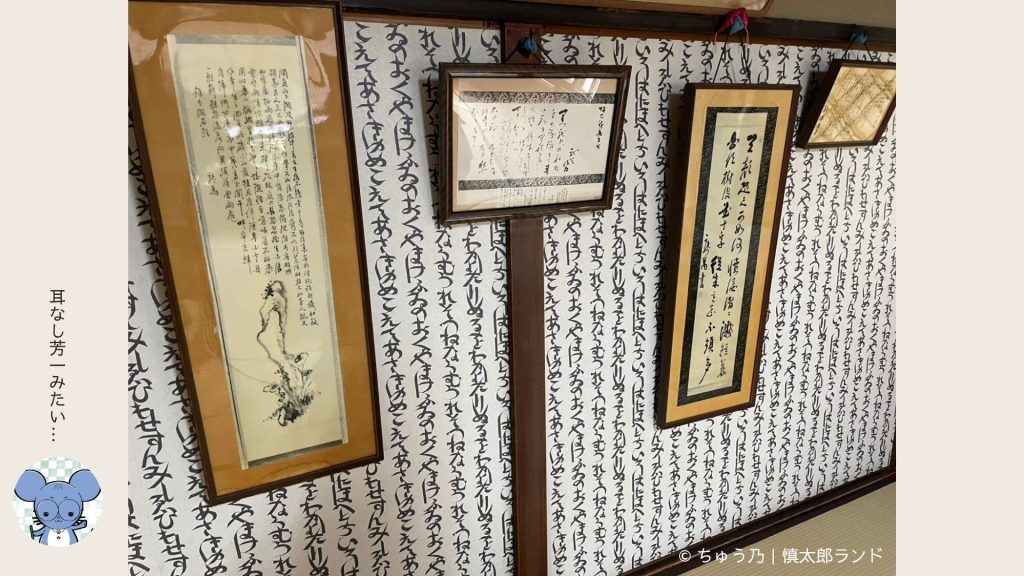 文字で埋め尽くされた壁紙に書や額が多数展示された寺田屋内部の部屋